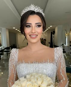 a woman wearing a tiara and holding a bouquet of flowers in her hands, smiling at the camera