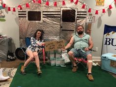 a man and woman sitting on chairs in front of a small camper with a sign