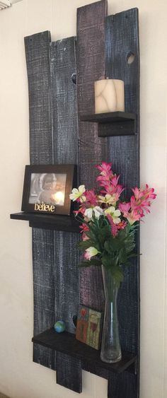 a vase filled with flowers sitting on top of a wooden shelf next to a wall