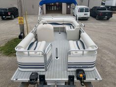 a white and blue boat parked in front of a building with two seats on the back