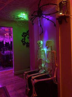 two skeletons are sitting in the corner of a room with purple and green lights on