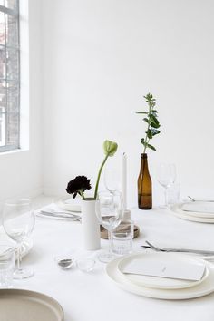 the table is set with white plates and wine glasses