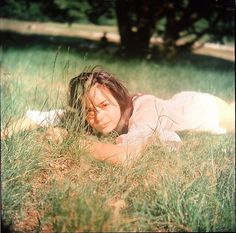 a woman laying in the grass with her eyes closed