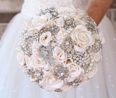 the bride's bouquet is made up of white roses and pearled brooches