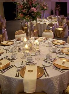 the table is set with gold and white plates, silverware, napkins, and candles