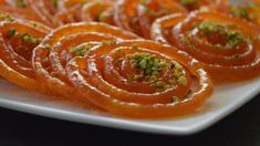 sliced oranges on a white plate topped with pistachio