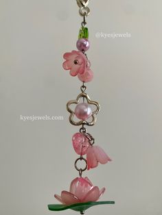 a pink flower is hanging from a metal chain with beads and glass flowers on it