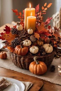 a basket filled with lots of pumpkins sitting on top of a table next to a candle