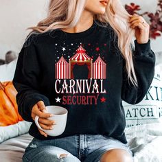 a woman sitting on a bed holding a coffee cup and wearing a carnival security shirt