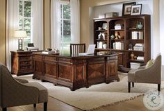 a large wooden desk sitting in the middle of a living room next to two chairs