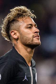 a close up of a soccer player wearing a black shirt and looking off to the side