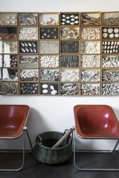 two red chairs sitting next to each other in front of a wall with pictures on it