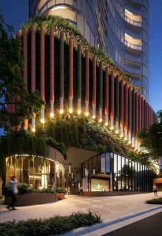 a tall building with many plants growing on it's side and people walking by