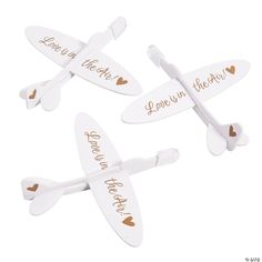 three white airplane shaped magnets with gold hearts on the sides and words that say love in the air