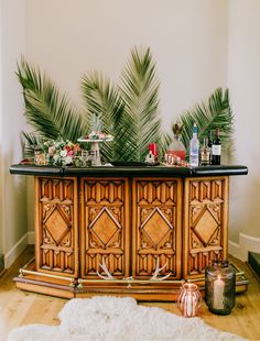 a buffet table with palm leaves on top and candles next to it, in front of a white wall