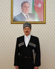 a man standing in front of a portrait of a man wearing a turban