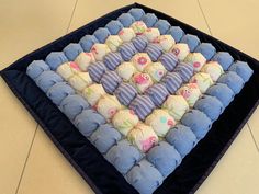 a blue and white blanket with many baby ones in it on the floor next to each other