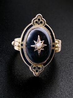 The Victorian Era was a hot time for all things celestial. When Halley's comet soared across the heavens in 1835, star themed jewelry was sought after by all the fashionable ladies and gentlemen!  Tiaras, necklaces and of course, brooches were embellished with star motifs, symbolizing a modern age, and to the sentimental Victorians, hope. The trend continued well into the Edwardian Era, with Queen Alexandra being known for wearing countless star brooches across her bodice. Introducing "Dark Angel"-a stunning addition to anyone who collects antique jewelry! Crafted in 12 karat gold, it has an onyx cabochon with a seed pearl star motif center. Accented with black enamel, it may have once been worn as a mourning ring. An altogether fabulous piece, and of course, it will pair so well with our Onyx And Pearl Ring, Victorian Pearl Jewelry, Dark Rings Aesthetic, Victorian Celestial, Victorian Wedding Ring, Jewelry Mood Board, Halley's Comet, Queen Alexandra, Elven Jewelry