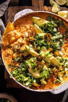 a dish with tortilla chips, avocado and other toppings