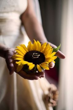 a bride holding a sunflower in her hand with the letter e on it's center