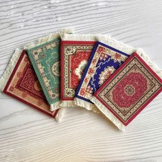 four different rugs laid out on top of a white wooden table with one red, one blue and one green