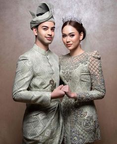 two people are dressed in traditional clothing and posing for the camera with their arms around each other