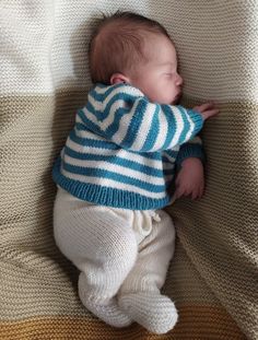 a baby is sleeping on a blanket wearing a blue and white striped sweater with stripes