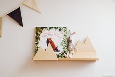 a wooden shelf with some books on it and two animals sitting on top of it