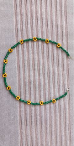 a green beaded necklace with yellow flowers