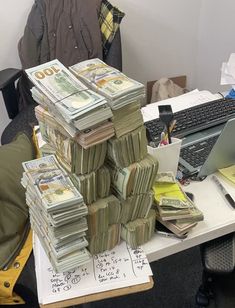 stacks of money sitting on top of a desk next to a computer