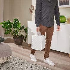 a man holding an air conditioner in his hand and standing next to a living room