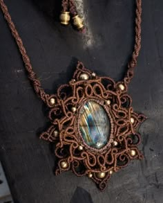 a necklace and earring made out of brown string with an oval glass bead in the center