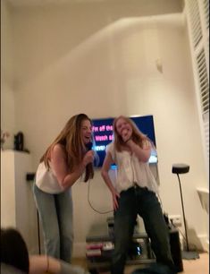 two young women standing in front of a tv