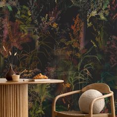 a chair and table in front of a wallpapered with plants on the walls