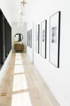 a long hallway with pictures on the wall and wooden flooring in front of it