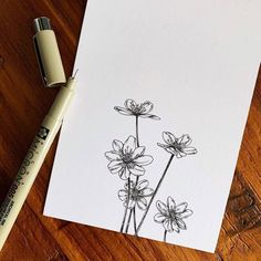 a drawing of some flowers on a piece of paper next to a marker and pen