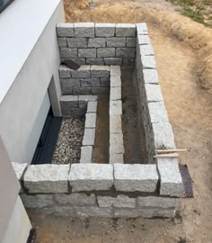 a cinder block wall with a door and window in the middle, surrounded by gravel