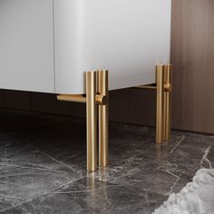 a white cabinet with gold handles on the top and bottom, sitting on marble flooring