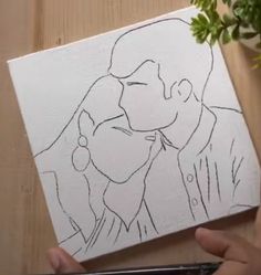 a drawing of a man and woman kissing on a piece of paper with flowers in the background