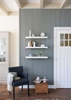 a living room filled with furniture next to a white door and shelves on the wall