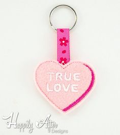 a pink heart shaped keychain with the words true love on it's side