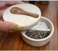 a person holding a wooden spoon over a bowl with some white stuff in it on a table