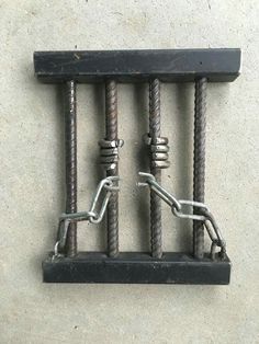 two metal bars are connected to each other on the concrete floor with chains hanging from them