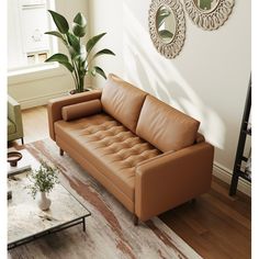 a brown leather couch sitting on top of a wooden floor next to a white rug