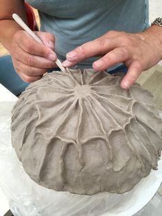 a woman is decorating a vase with clay and white crayon pencils