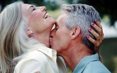 an older couple kissing each other in the park