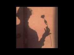 the shadow of a man holding a rose in his hand and looking down at it