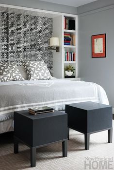 a bed with white sheets and pillows in a bedroom next to a book shelf filled with books