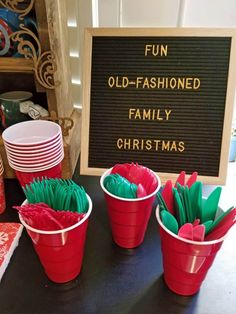 red buckets filled with green paper flowers sitting next to a sign that says fun old - fashioned family christmas