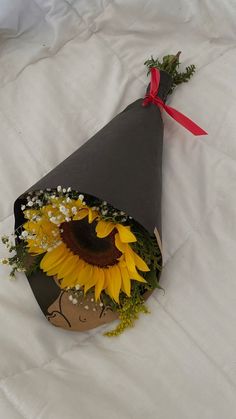 a paper cone with sunflowers and baby's breath in it on a white sheet